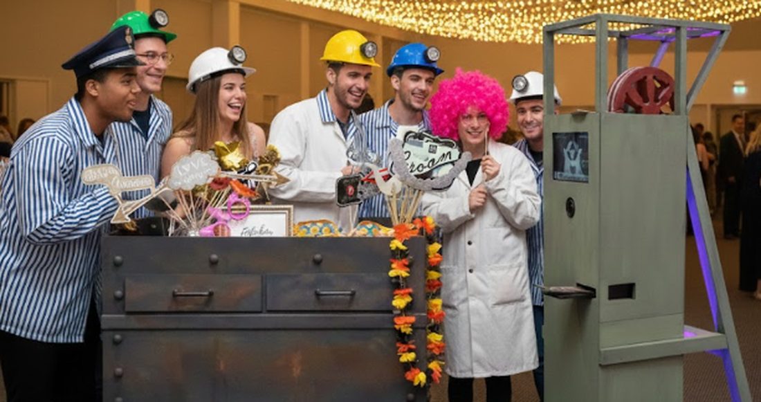 Gäste einer Feier mit Helmen und Perücke an der Fotobox Der Fototurm